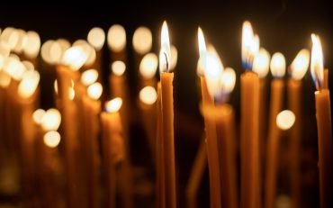 Close view of lots of burning candles with black background